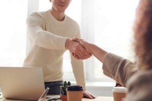 man and woman shaking hands over a table