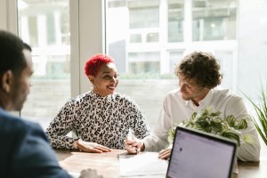 Three people smiling at a table doing financial paperwork