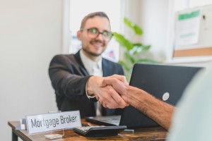 Mortgage broker and client sealing a deal with a handshake in a bright, modern office